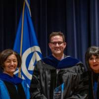 Provost and President take picture with man holding glass trophy award